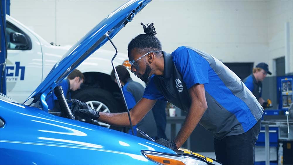 A J-Tech Automotive Technician student working with a diagnostic tablet in the lab.