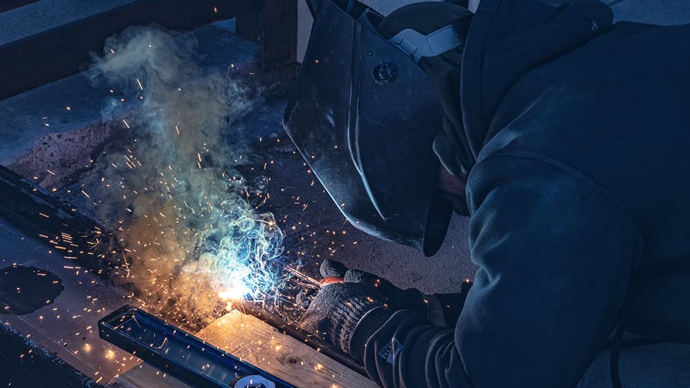 A welder working hands on with tools.