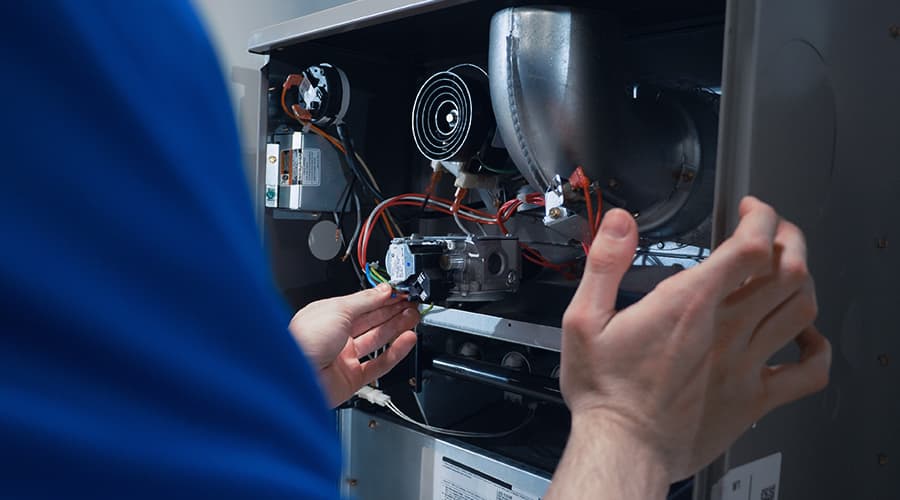 A J-Tech HVAC-R student working hands-on with an electrical panel.