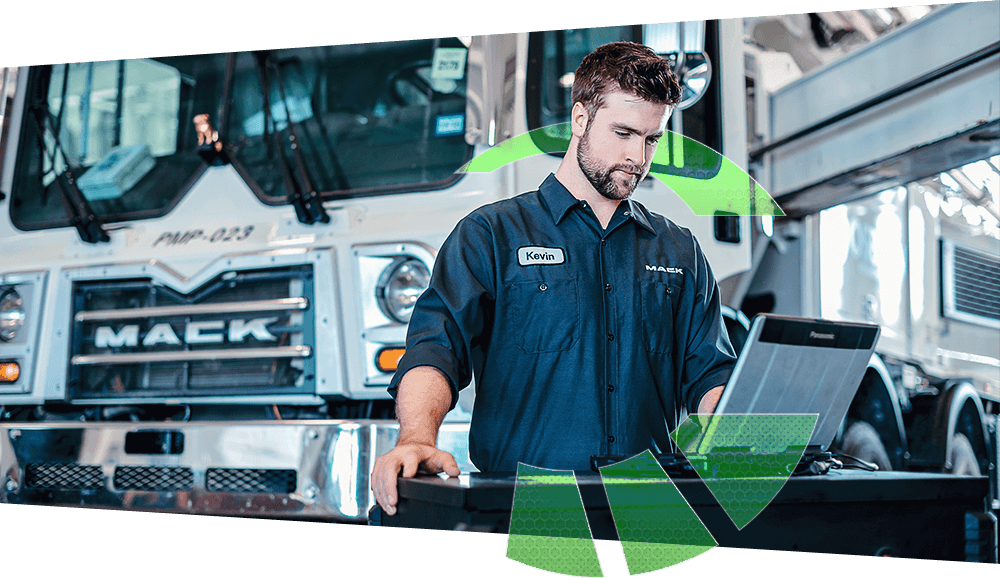 A Mack technician diagnosing a truck with a laptop.