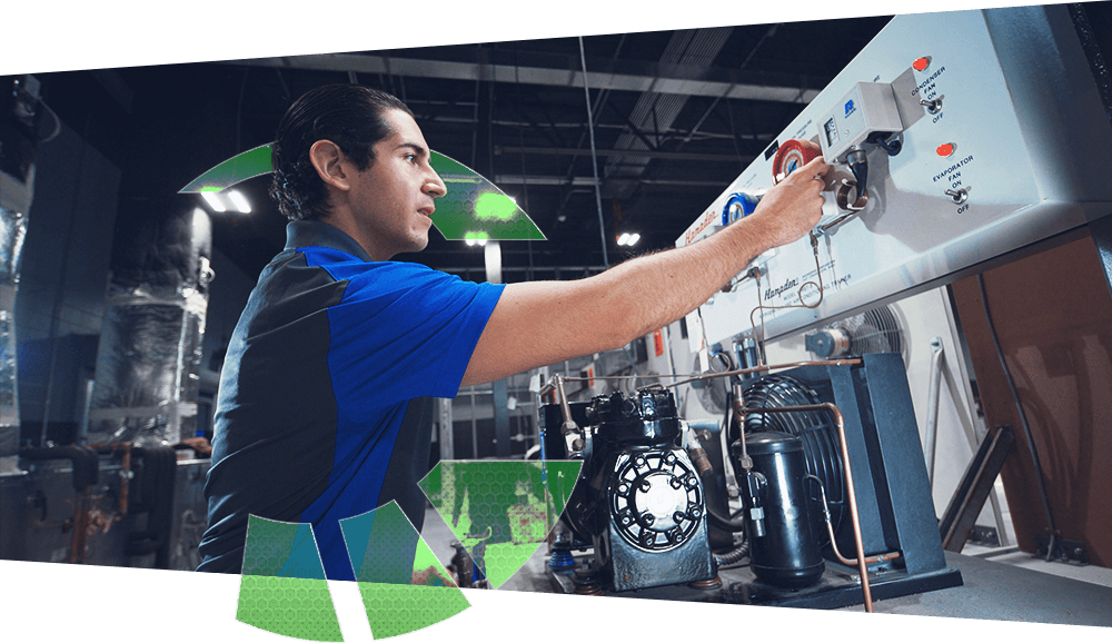 A J-Tech HVAC-R student working hands-on in the lab, adjusting a knob.