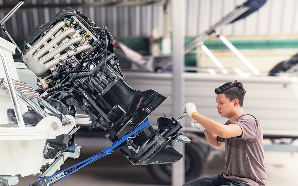 A marine technician working on an outboard engine.