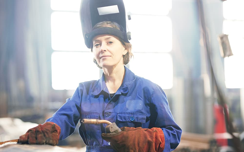 Smiling female welder in a factory