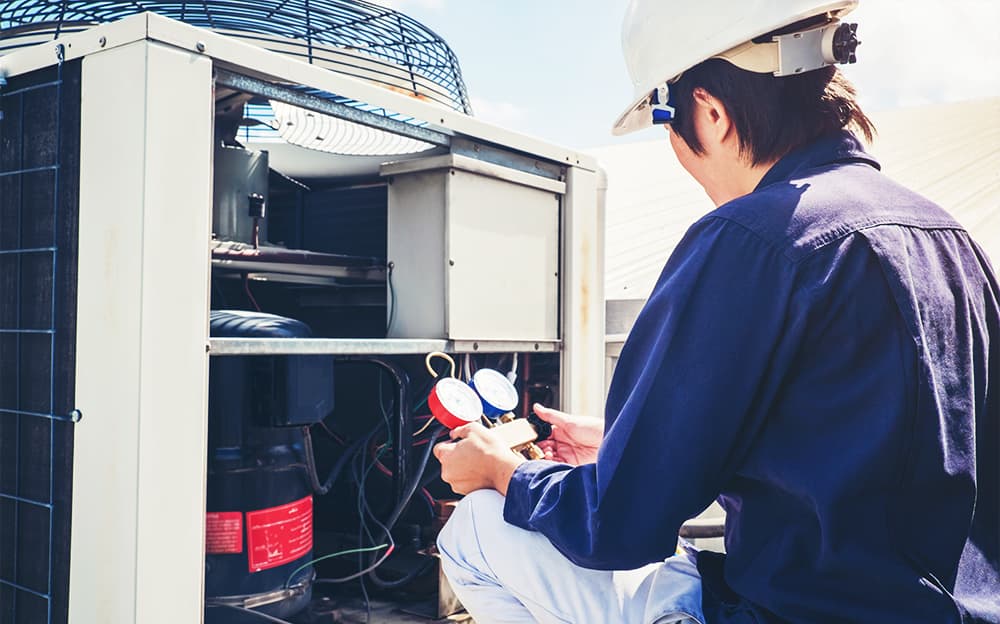 HVAC technician checking an air conditioner with gauges.