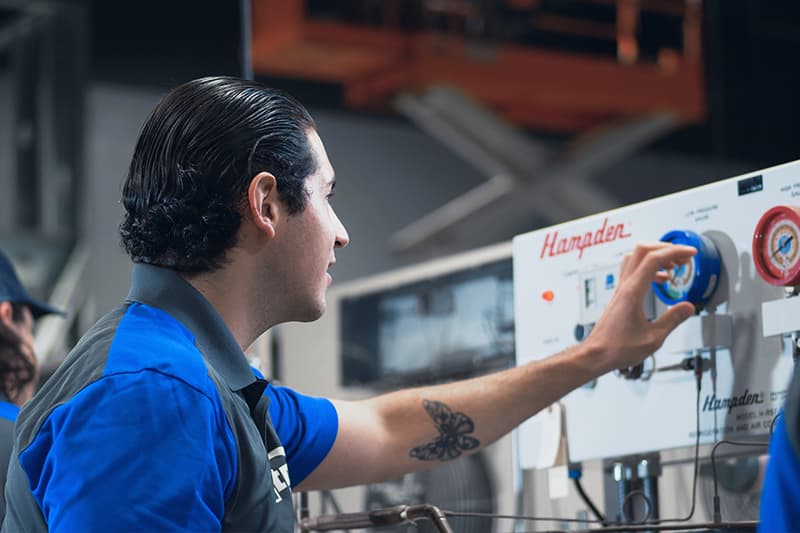 Photo of a J-Tech HVAC-R student working in the lab, turning a knob.