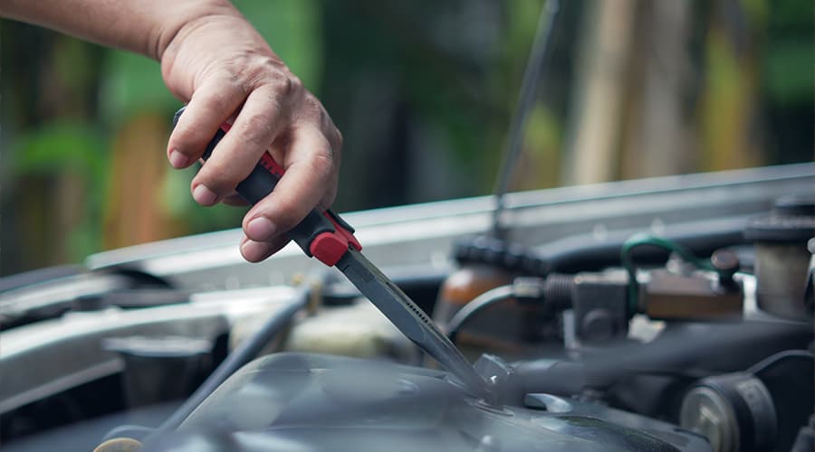 Close-up of a hand holding a wrench, tightening a bolt on a car engine.