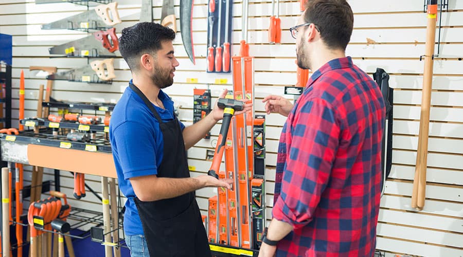 A teenage boy working at a hardware store, helping a customer.