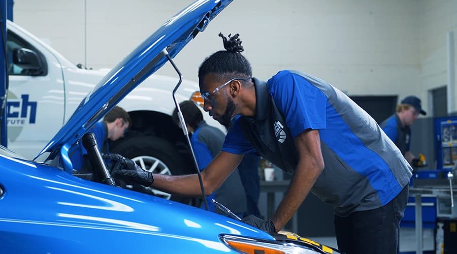 A J-Tech Automotive Technology student using a tablet to diagnose a car.