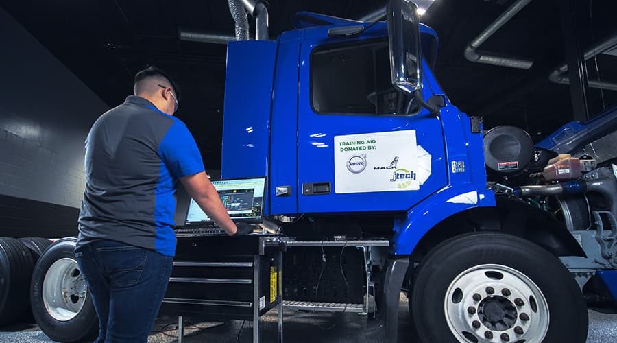A J-Tech Diesel Technology student using a laptop to monitor and diagnose a semi truck.